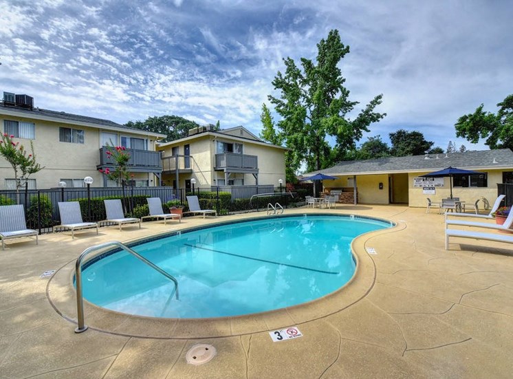 Rocklin CA Apartments for Rent - The Everette - Pool Area with Lounge Chairs, Blue Umbrellas, and Poolhouse